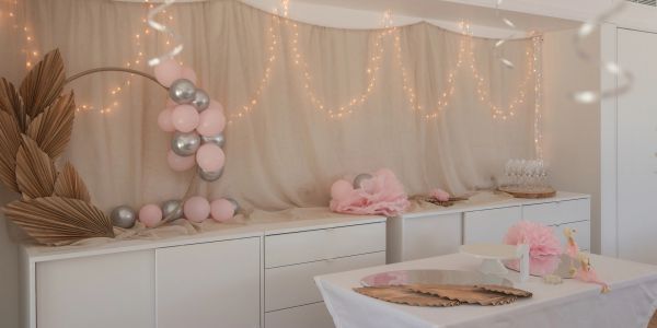 Elegant party setup with pink and silver balloons and fairy lights.