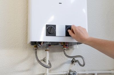 Hand adjusting gas water heater control knob.
