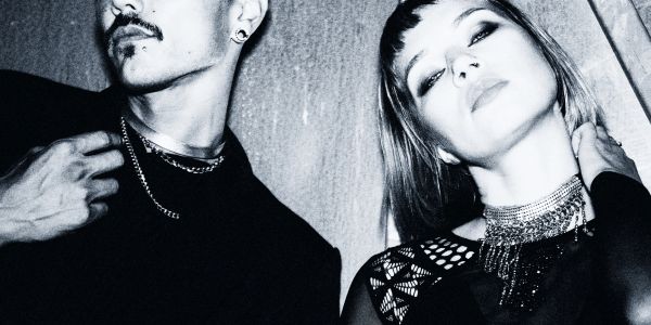 Black and white portrait of two stylish people with bold accessories and confident expressions.