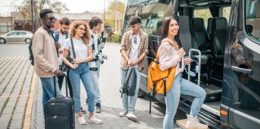 Grupo de jóvenes abordando un autobús con equipaje.