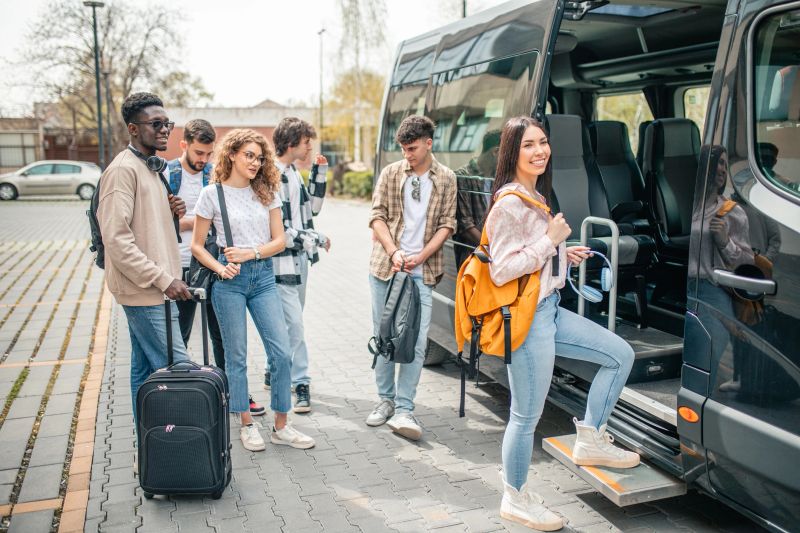 A multiracial group of young passengers board the minibus one by one