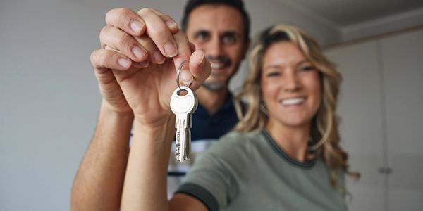 Happy couple holding keys to their new home, smiling.