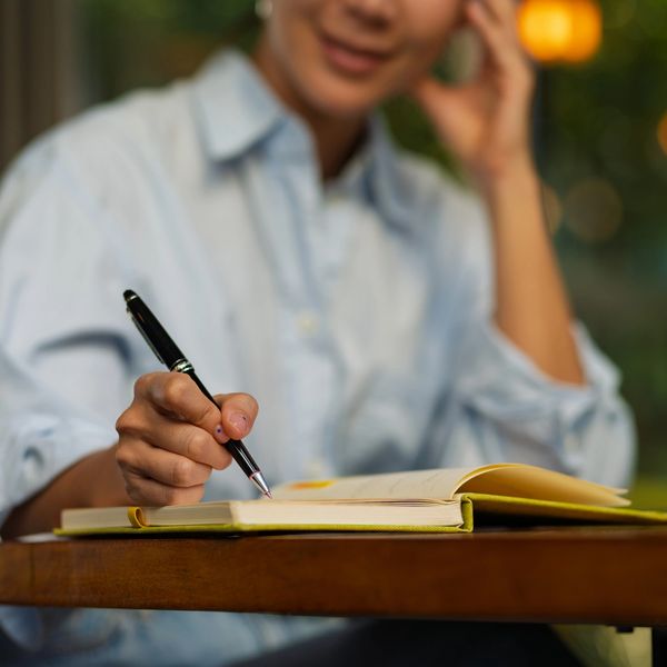 A person writing by hand in a journal