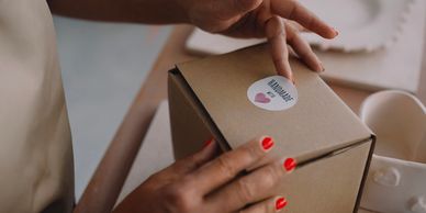 Hands opening a cardboard box with a 'Handmade' sticker.