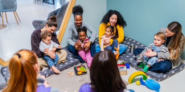 Group of parents and toddlers playing and interacting indoors.