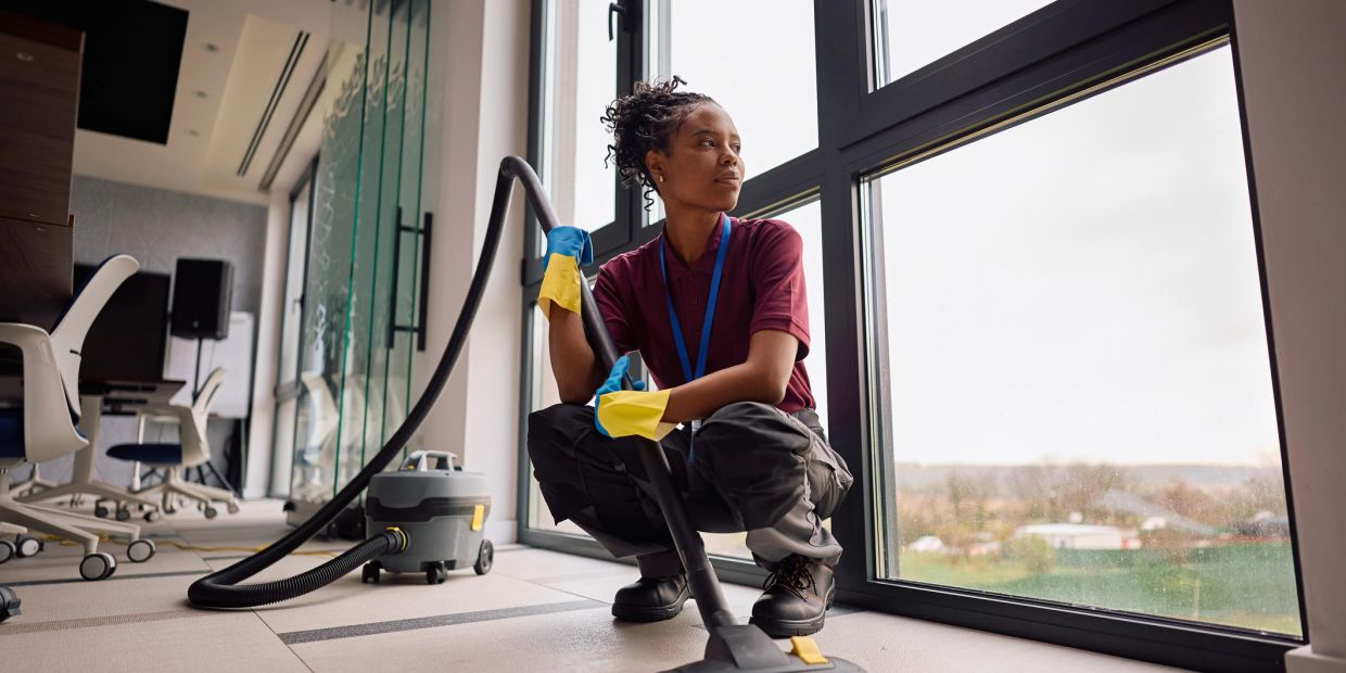 Professional cleaner using a commercial vacuum cleaner in an office building