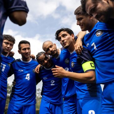 Soccer team huddles together in blue jerseys before a game.
