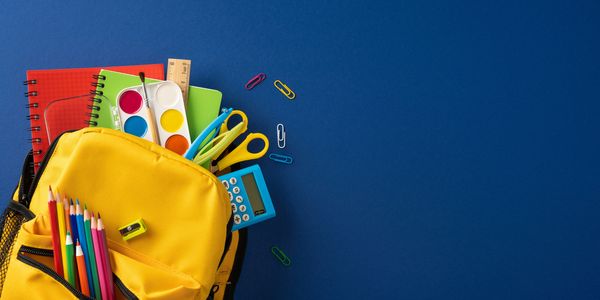 Yellow backpack filled with school supplies on blue background.