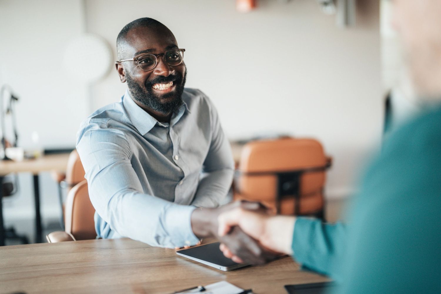 Man smiling during a handshake in a business setting.