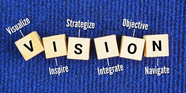 Wooden blocks spell out VISION with related words.