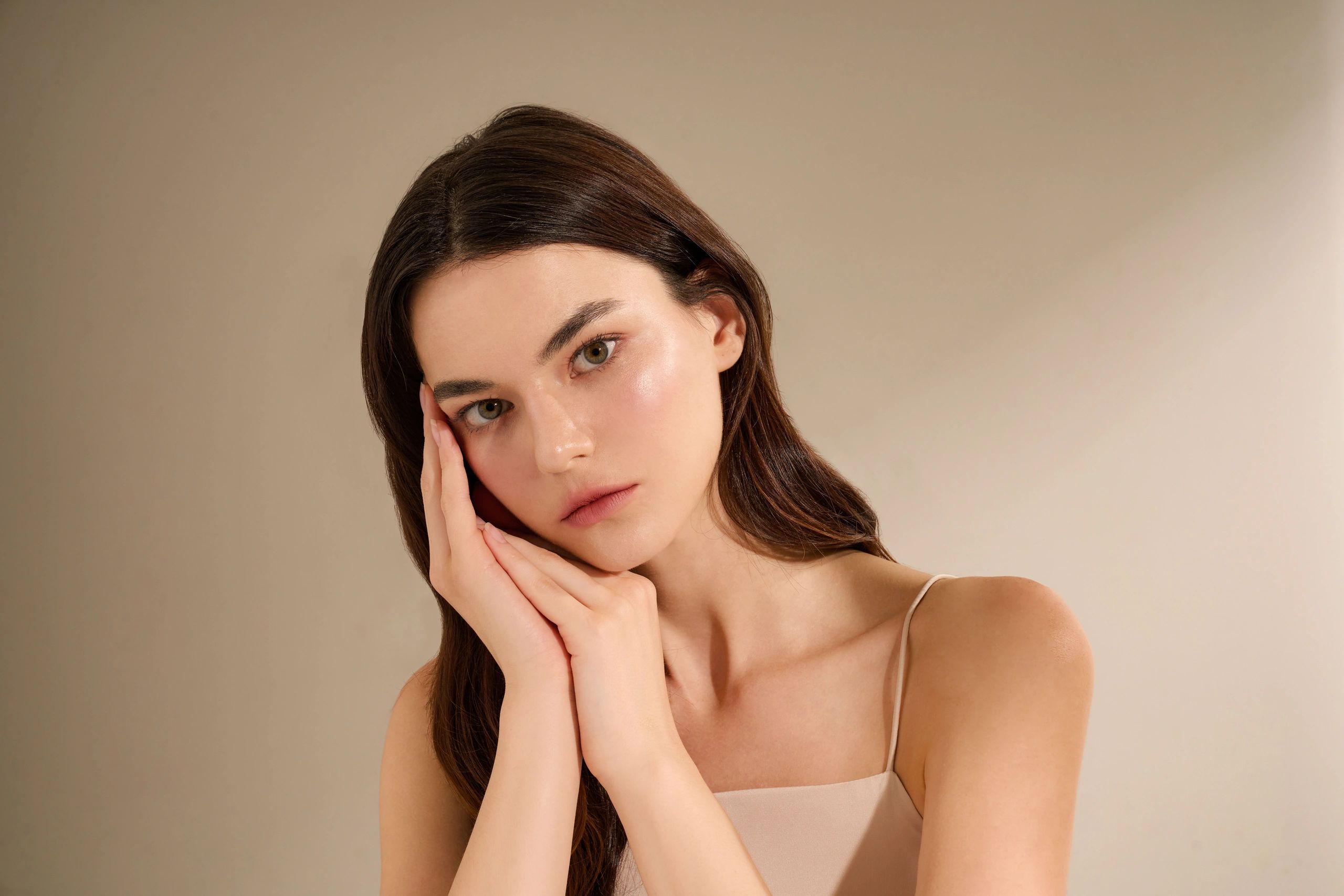 Woman with smooth hydrated cheek skin on a warm beige background