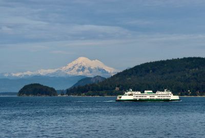 Ferry on water with snowy mountain in background.