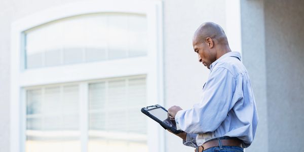 Man using a tablet outside a house.