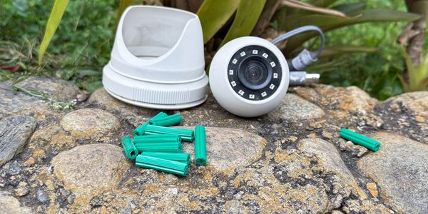 A security camera and mounting accessories on a rock outdoors.