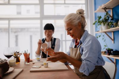 Two women enjoying a pottery painting activity together in a bright studio.