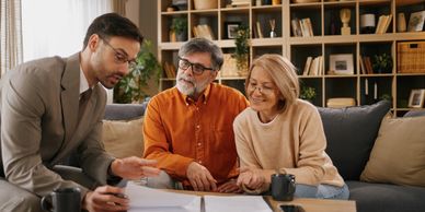 Financial advisor explaining documents to senior couple at home.