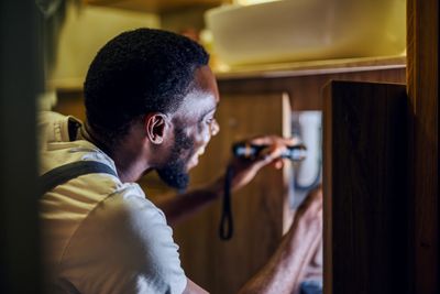 Man fixing plumbing under a sink.