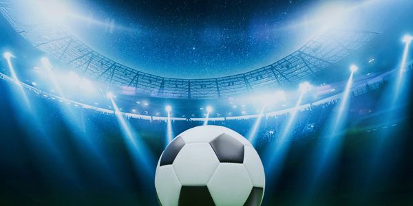 Soccer ball in a brightly lit stadium under a night sky.