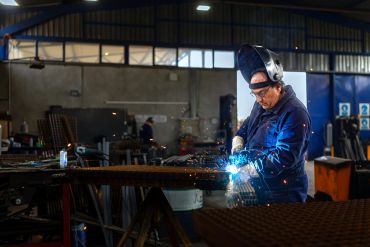 Man welding metal in workshop with sparks flying.