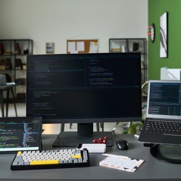 Technology professional reviewing digital systems across multiple monitors.