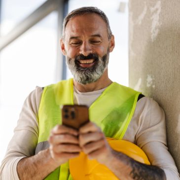 Blue-collar tradesman in a hi-vis vest talking on his phone