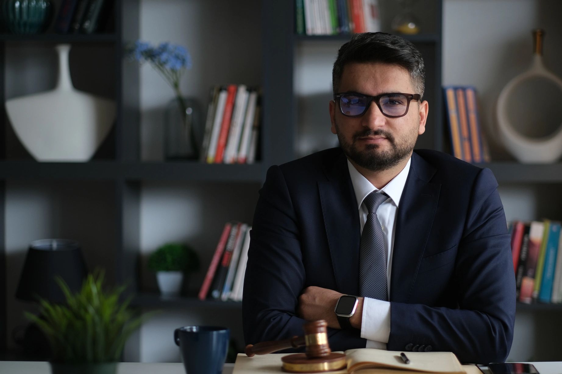 Confident man in a suit sitting with arms crossed in an office.