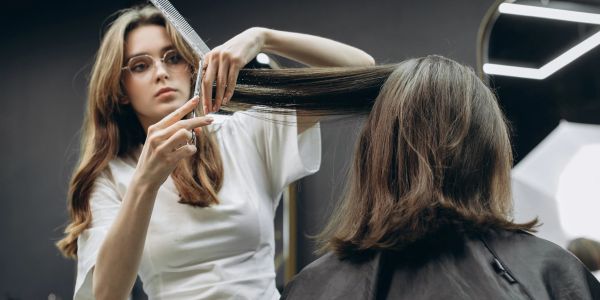 Hairdresser carefully trims client's long hair in a modern salon.