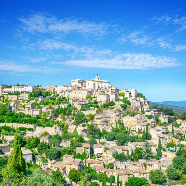 Scenic hilltop village with stone houses under a bright blue sky.