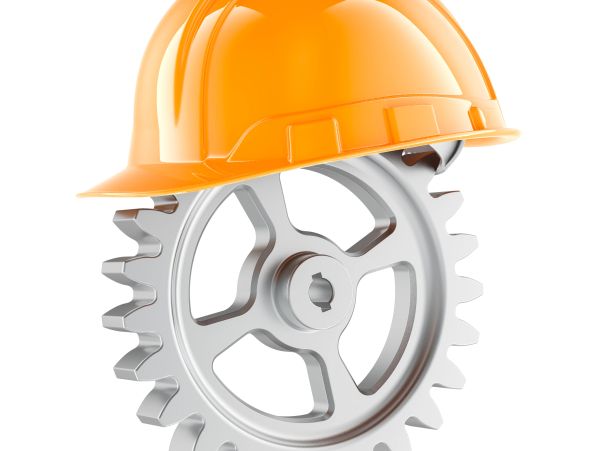 An orange construction helmet resting on a silver gear wheel.