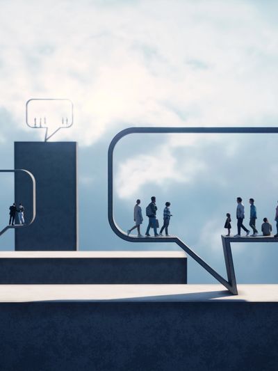 People walking inside large speech bubble shapes against a cloudy sky.
