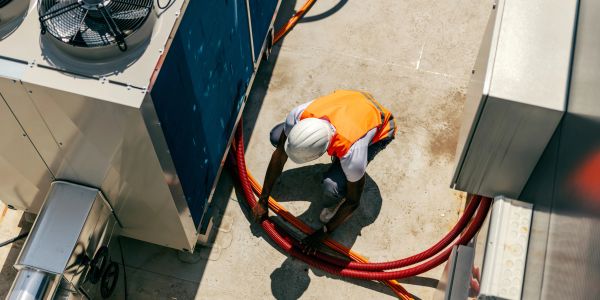 Worker handling electrical cables on rooftop.