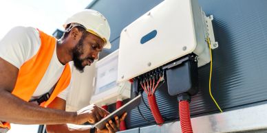Engineer inspecting electrical panel with tablet.