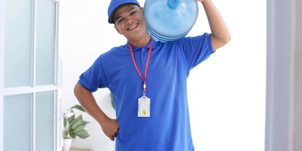 Delivery man carrying water jug on shoulder.