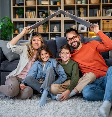 Happy family sitting on the floor under a makeshift roof.