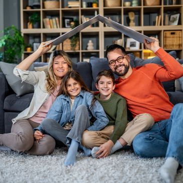 Happy family making a roof shape with a laptop indoors.