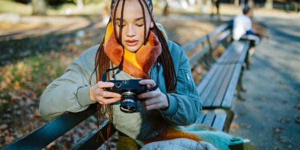 Woman sitting on a park bench looking at a camera.