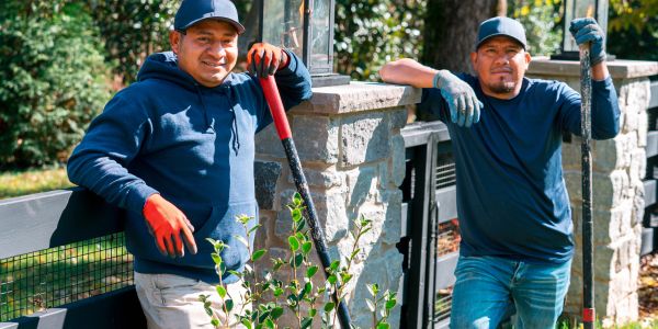 Two men gardening outdoors smiling.