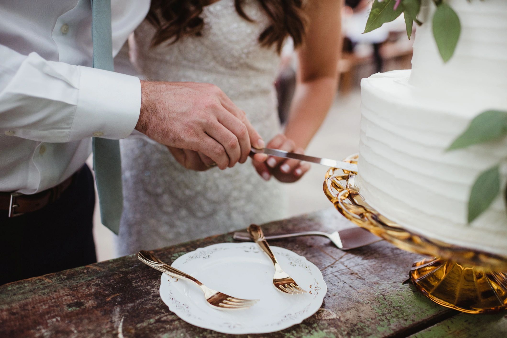 Couple cutting wedding cake together.
