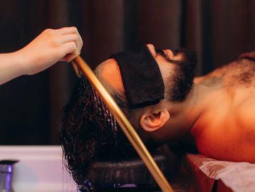 Man getting hair wash with a towel over eyes.