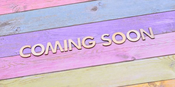 Wooden letters spelling 'COMING SOON' on pastel wooden planks.