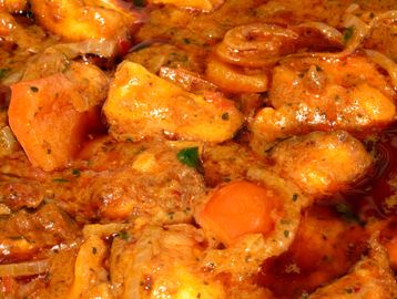 Close-up of a rich, orange stew with chunks of meat and vegetables.