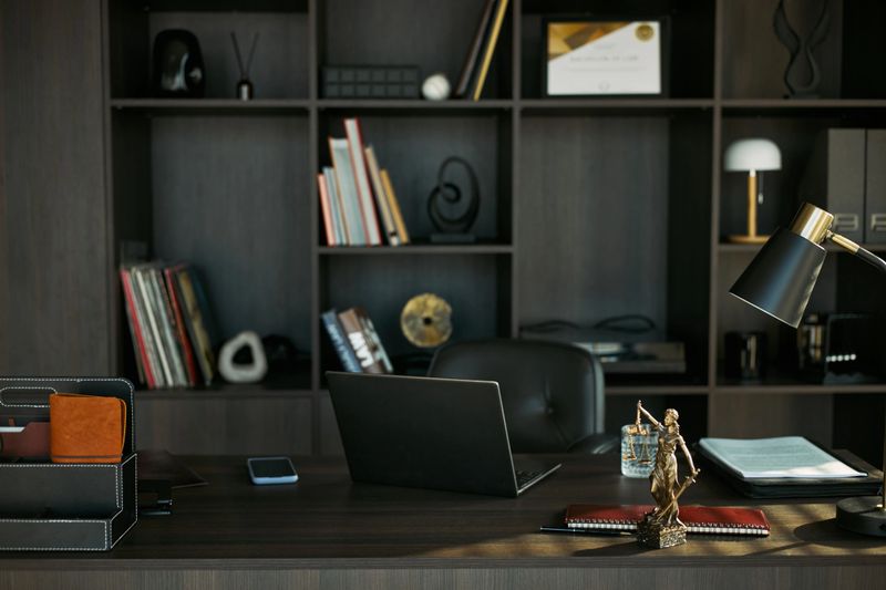 Wide shot of lawyer office desk displaying laptop, legal files, justice statue, suggesting divorce consultation and family law services. Suitable for legal marketing, mediation, custody content