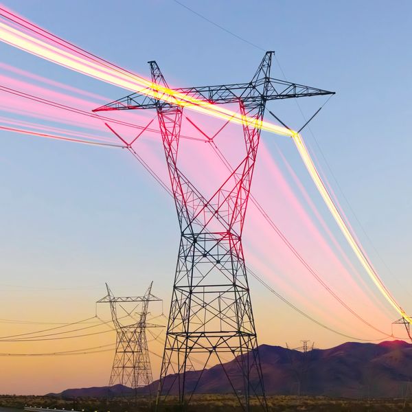 Gün batımında yüksek gerilim elektrik direkleri ve ışık izleri.