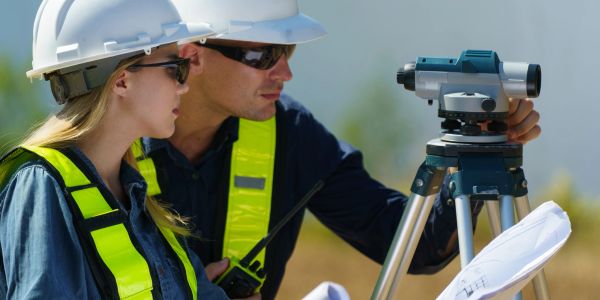 Two surveyors using equipment outdoors.