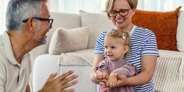Grandparents joyfully interacting with their granddaughter at home.