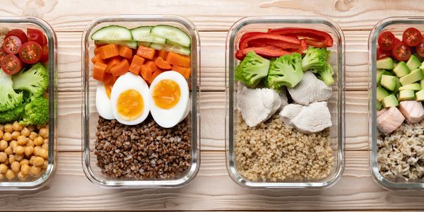 Glass containers with healthy meals including eggs, vegetables, and grains.