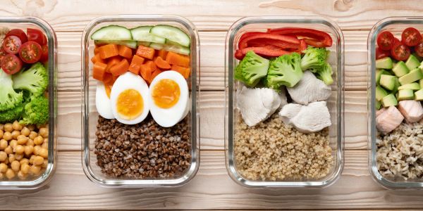 Glass containers with healthy meals including eggs, vegetables, and grains.