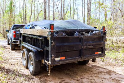 Trailer filled with black bags covered by a tarp, attached to a truck.
