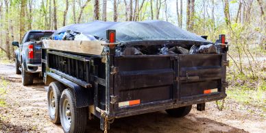 Truck towing a trailer full of covered waste bags.