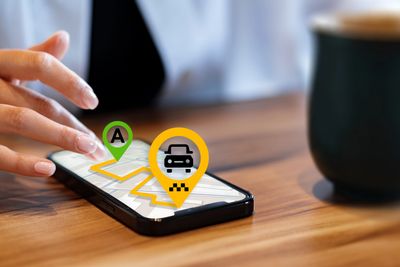 Person using taxi app on smartphone at a table.